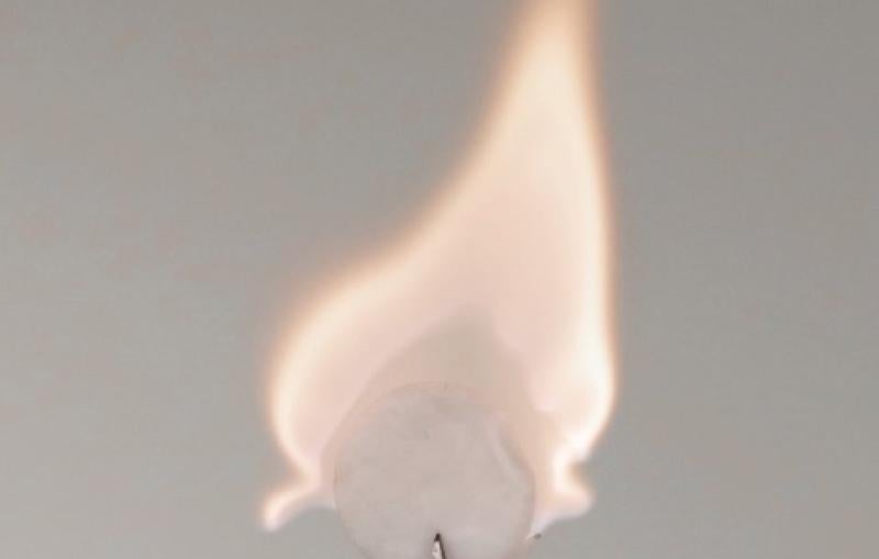 A white disc of battery material catches fire.