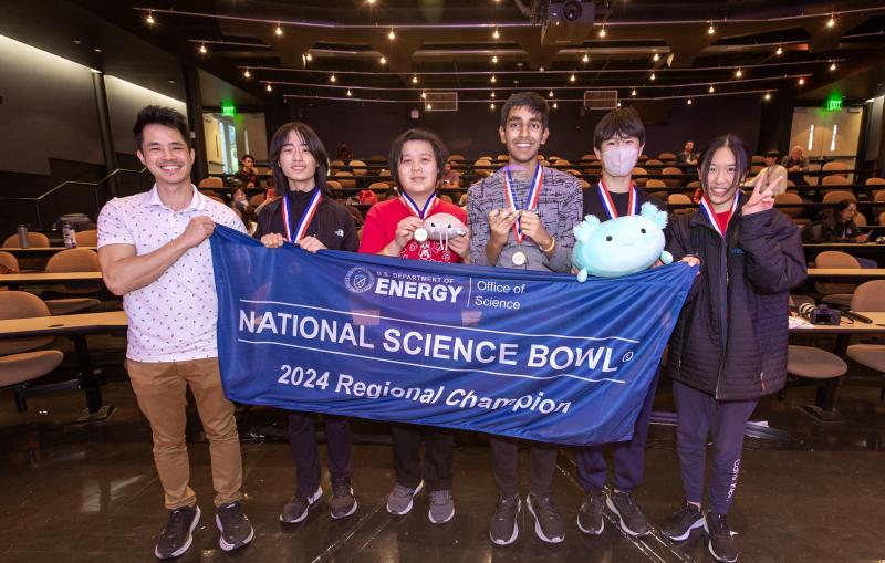 High school students hold up a blue National Science Bowl banner.