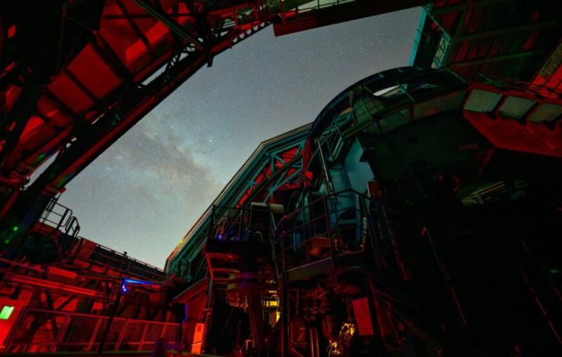 A telescope pointed through open doors in its building's roof.