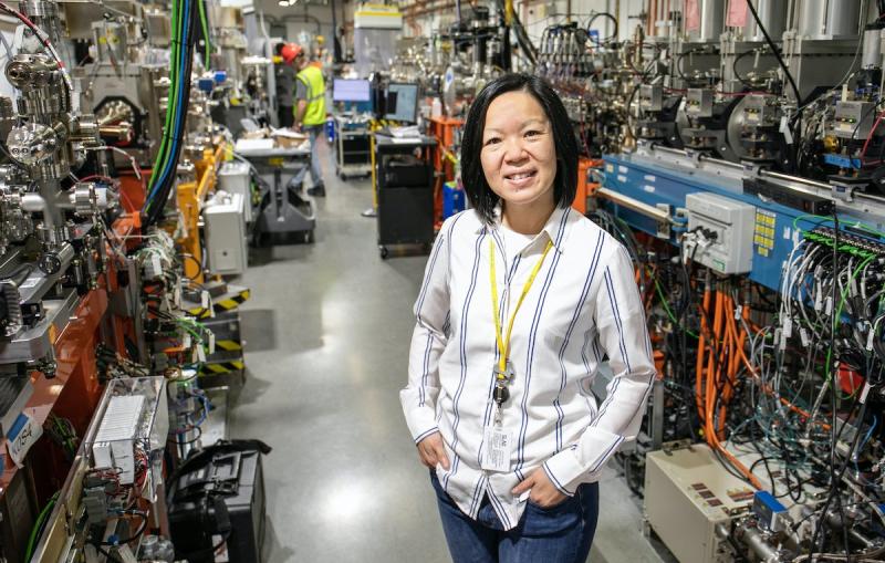 A woman stands in a long hallway with scientific equipment