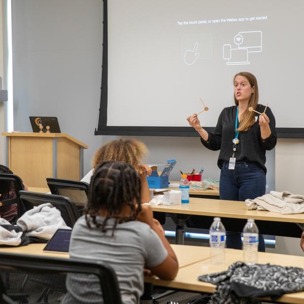 A teacher speaks in front of a classroom of students.