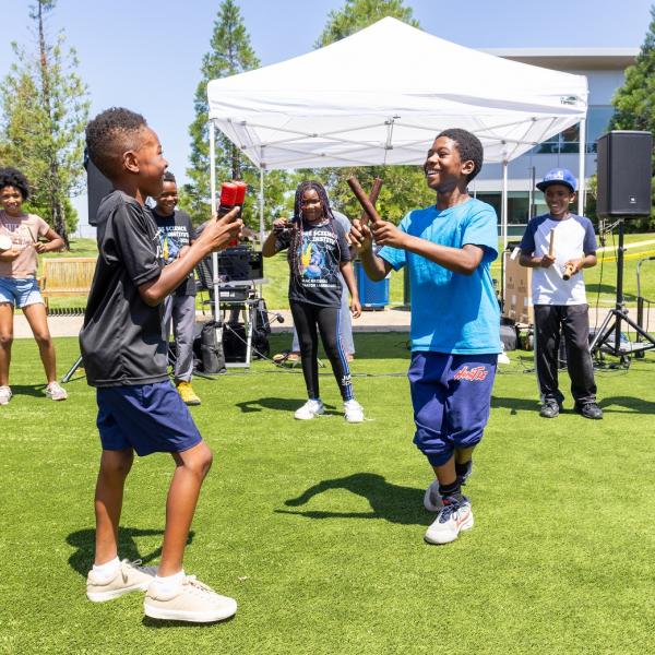 Students sing and play music outside. 