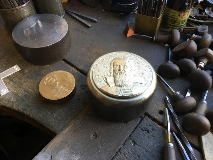 A bronze medal and tools on a table in a workshop.