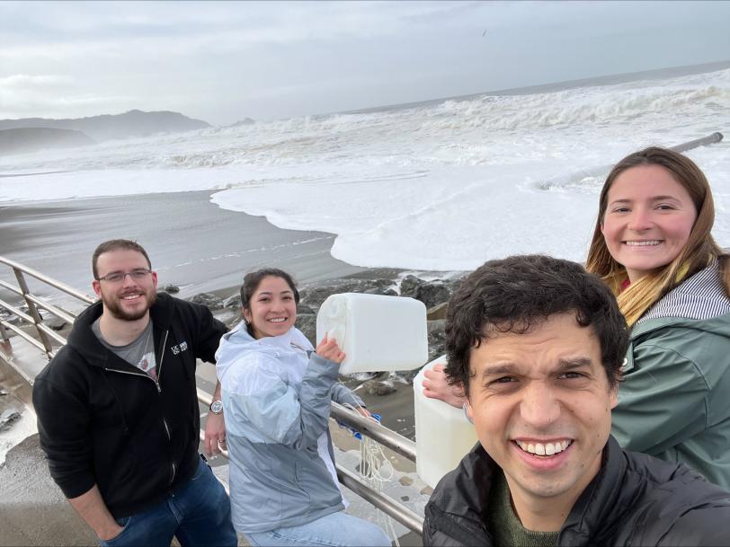 Researchers stand near the Pacific Ocean holding buckets in which they collected seawater for an experiment to turn seawater into hydrogen fuel.