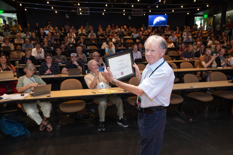 Photo of a man holding an award plaque. 