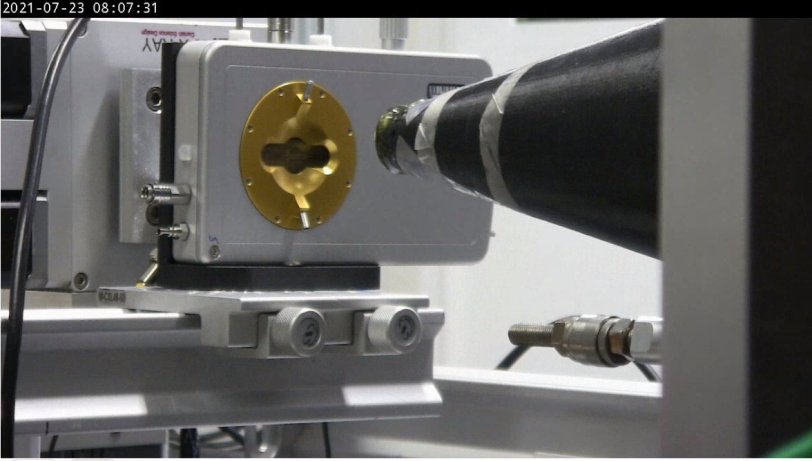 An X-ray beam line guide points toward a gold-colored piece of laboratory equipment.