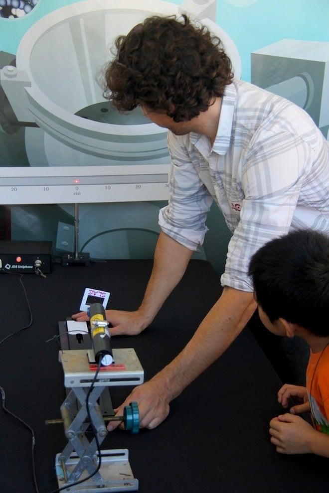 Photo - A child watches as SLAC's Daniel Ratner measures the width of his hair