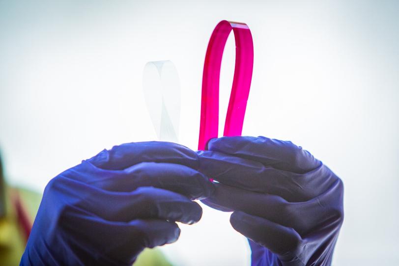 Image - A researcher at SLAC's Stanford Synchrotron Radiation Lightsource holds up a thin strip of material printed with an ink (magenta) relevant to solar-energy conversion.