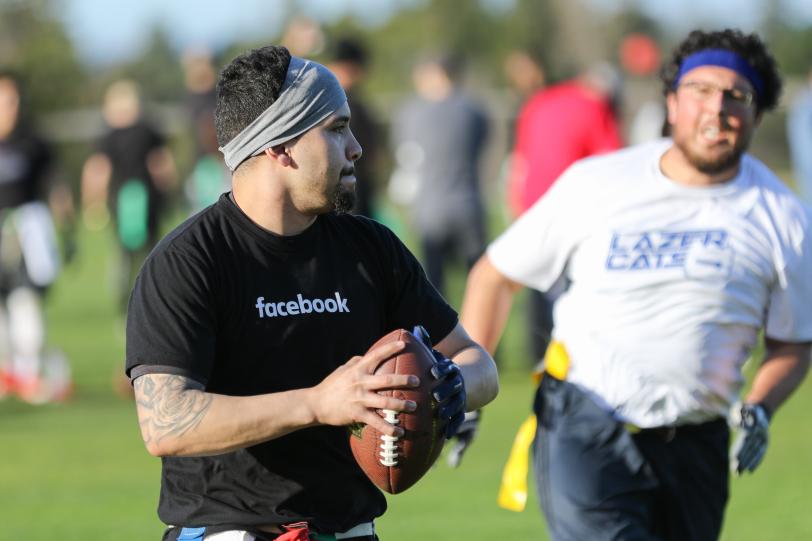 A Facebook player throws a ball with a Livermore player in the background