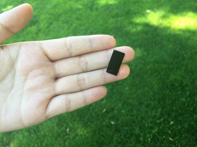 A researcher holds a tiny device that uses sunlight to disinfect water.