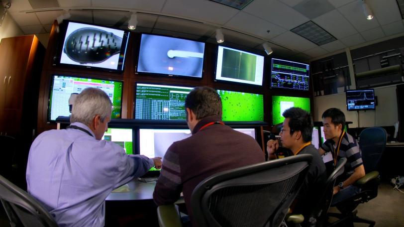 Image - From left, Axel Brunger, Artem Lyubimov, Qiangjun “John” Zhou and Minglei Zhao, view images from an experiment at SLAC’s Linac Coherent Light Source, an X-ray free-electron laser. Researchers used a robotic setup to zap tiny, frozen crystals.