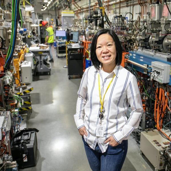 A woman stands in a long hallway with scientific equipment